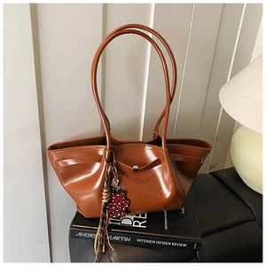 Detail of caramel glossy tote bag with leopard charm on a minimalist interior background