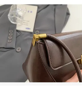 Detail of dark brown leather baguette bag with vintage matte gold metal hardware
