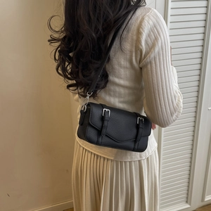 Primer plano de bolso bandolera de cuero granulado negro con hebillas plateadas en modelo