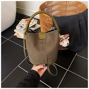 Nahaufnahme der mattgrünen Beuteltasche mit Plüschbären-Anhänger und Markenlogo