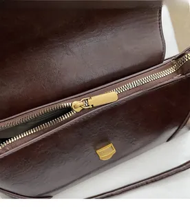 Detailed close-up of smooth gold zipper and glossy dark brown leather bag texture