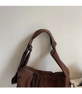 Nahaufnahme des breiten Schultergurts und der braunen Gittertextur der Nylontasche