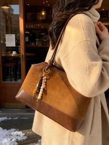 Borsa tote vintage in pelle scamosciata marrone con ciondolo in legno in un caffè invernale