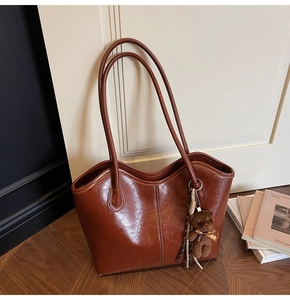 Detail of vintage brown leather tote bag featuring a cute plush bear charm with Love ribbon