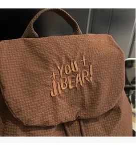 Detail of waffle-textured brown nylon backpack featuring YOU JIBEAR embroidery