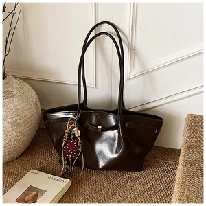 Detail of dark brown tote bag with glossy finish and red leopard print charm