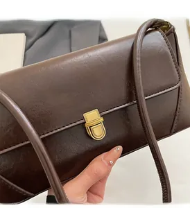 Close-up of vintage brown glossy leather handbag with antique gold metal buckle closure