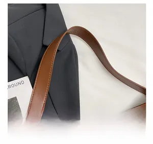 Detail of wide brown leather shoulder strap with vintage gold metal buckle on tote bag