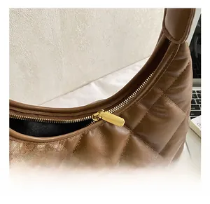 Close-up of golden zipper hardware and quilted leather texture on brown hobo bag