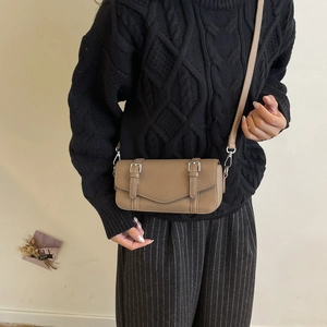 Primer plano del bolso caqui de cuero con textura de lichi y hebilla plateada elegante