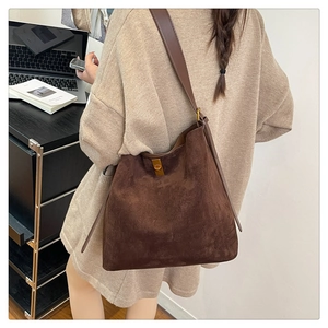 Detail of suede tote bag with adjustable shoulder strap and gold metallic buckle