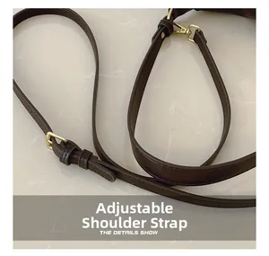 Detail of adjustable leather shoulder strap with gold-tone hardware on brown handbag