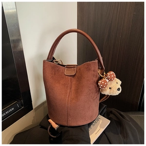 Detail der Beuteltasche aus Wildleder in Caramel mit Ledergriff und Bärenanhänger