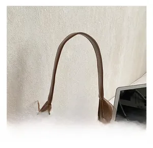 Detail view of the brown quilted tote bag showing sturdy handle and metal chain accessory