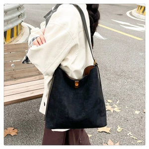 Close-up of black suede tote bag with golden buckle during an outdoor street shoot