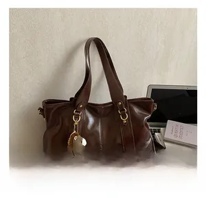 Makroaufnahme der dunkelbraunen Ölwachs-Leder-Tote mit Pony-Anhänger und Laptop-Deko