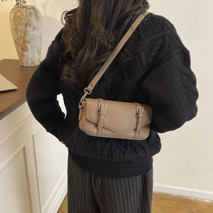 Bolso bandolera caqui texturizado llevado por una modelo en un cálido ambiente interior