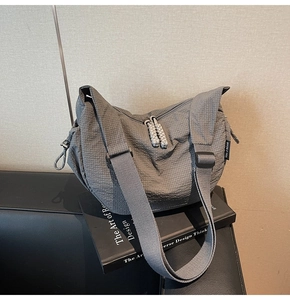 Detail der grauen Canvas-Tasche mit gewebten Seil-Reißverschlüssen und verstellbarem Schultergurt