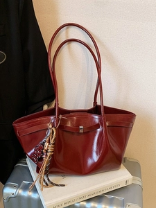 Large dark red patent leather tote bag with glossy finish and leopard tassel charm