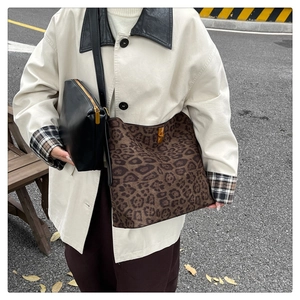 Outdoor shot of a leopard print tote bag with a matching black leather zipper pouch