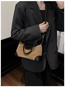Close-up of suede shoulder bag with leather contrast and gold buckle on a model
