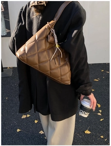 Detail view of large brown quilted leather hobo bag worn by a model in street style