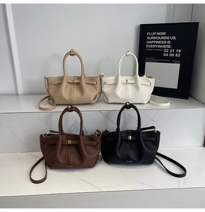Detailed view of bucket bags in beige, white, brown, and black with pebble leather texture