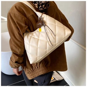 Detail of white quilted leather hobo bag with tassel and yellow smiley face charm