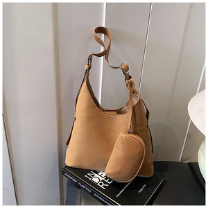 Brown leather hobo bag with adjustable strap and small zipper pouch on design books