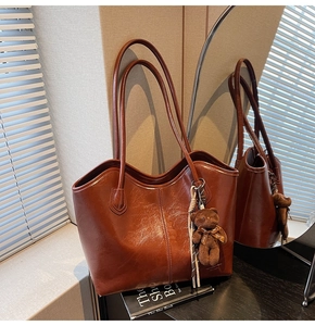 Close-up of caramel leather tote bag with a cute brown plush bear charm detail