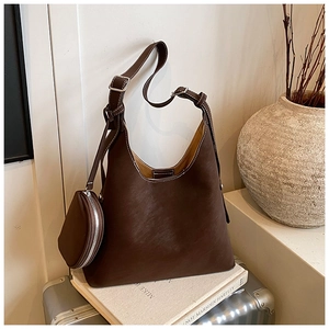 Detail of dark brown leather hobo bag with white stitching and round coin purse accessory