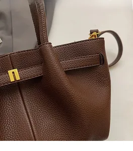 Detail of dark brown lychee grain leather handbag with gold metal square clasp