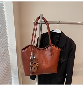 Detail of vintage brown tote bag with smooth finish and cute bear charm pendant
