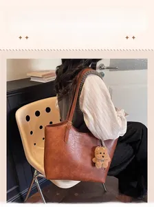 Detail shot of a large brown vintage leather tote bag worn by a model in a minimal room