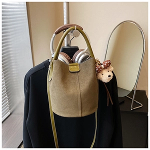 Detail der khakifarbene Wildleder-Beuteltasche mit Ledergriff und Bärenanhänger