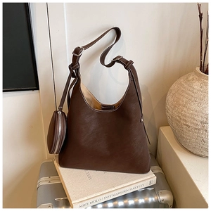 Detail of dark brown leather hobo bag with contrast stitching and mini round purse accessory