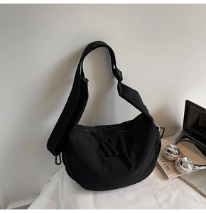 Detail der schwarzen halbmondförmigen Segeltuchtasche mit verstellbarem Schultergurt
