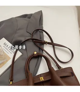 Detail of dark brown lychee grain leather handbag with adjustable thin shoulder strap