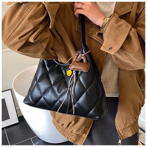 Close-up of black quilted shoulder bag with diamond pattern and cute hanging charms