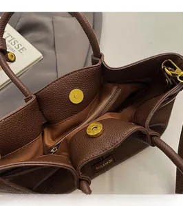 Detail of a dark brown lychee leather tote bag showing the magnetic snap and interior