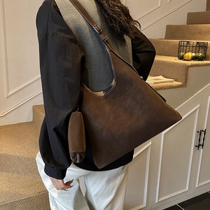Detail of a brown hobo bag featuring adjustable wide straps and a small matching pouch