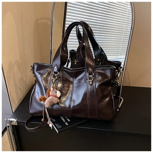 Vista dettagliata della borsa tote in pelle verniciata cioccolato con charm a cavallo