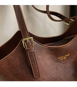 Detail of vintage brown leather tote bag with golden metal buckle and side logo