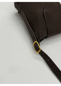 Détail de la bandoulière réglable en cuir avec boucle dorée sur un sac cabas marron foncé
