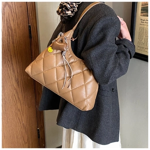Detailed shot of brown quilted hobo bag with yellow smiley face and heart charms