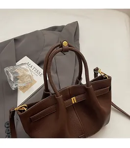 Close-up of dark brown lychee grain leather handbag with gold buckle and dual top handles
