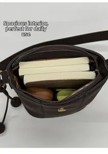 Vue macro montrant la grande capacité du sac seau en cuir mat marron avec objets du quotidien