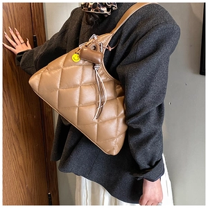 Brown quilted hobo bag with yellow smiley face charm and tassel on a female model