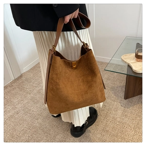Detail of suede tote bag with smooth leather handle and elegant gold metal twist lock