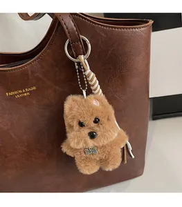 Detail of a plush brown puppy bag charm with metal ring and TOP DOG bone tag on a tote bag